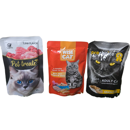 Three cat food packages on a grassy surface with a beige wall background